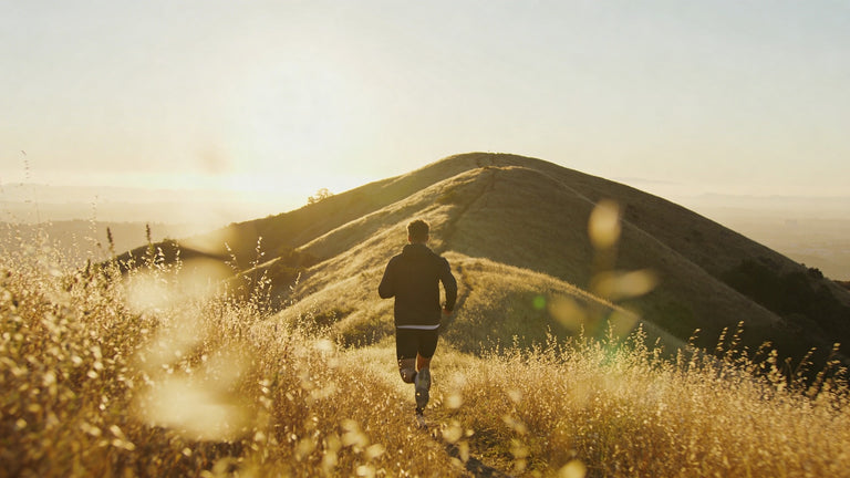 Person running on a path with a scenic view of a hill and sunset.